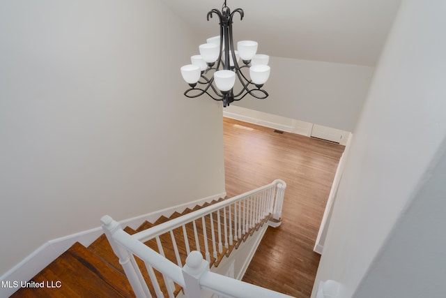 staircase featuring baseboards, a chandelier, and wood finished floors