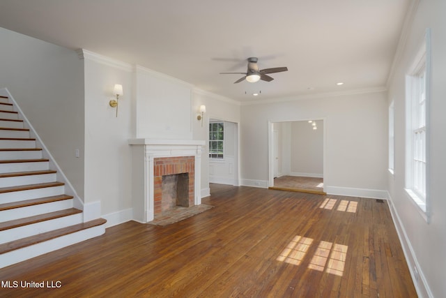 unfurnished living room with plenty of natural light, a fireplace, stairway, and hardwood / wood-style floors