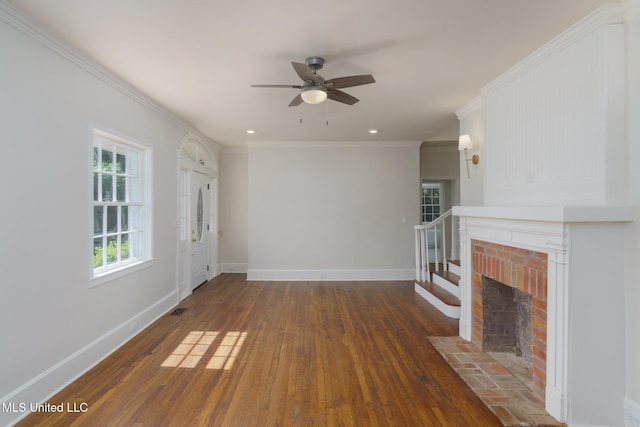 unfurnished living room with crown molding, visible vents, a brick fireplace, baseboards, and hardwood / wood-style flooring