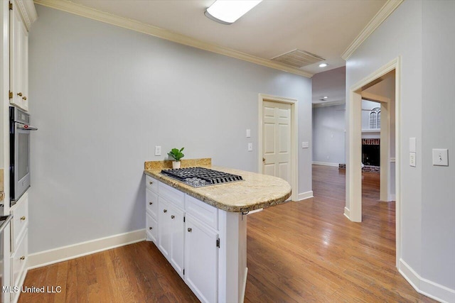 kitchen featuring a peninsula, stainless steel oven, white cabinets, light countertops, and ornamental molding