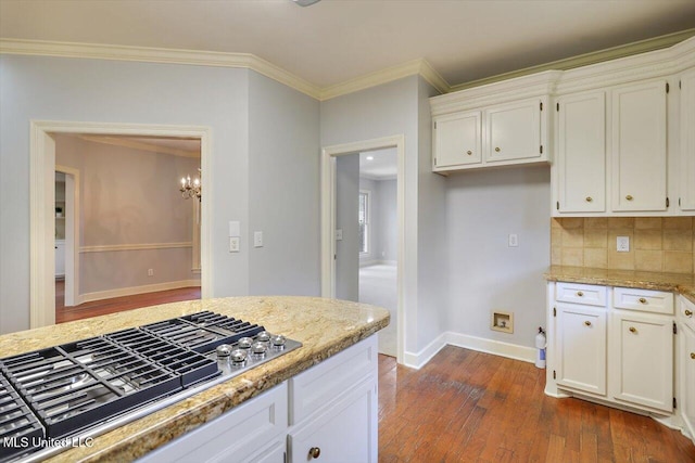 kitchen with crown molding, dark wood finished floors, light stone countertops, and stainless steel gas stovetop