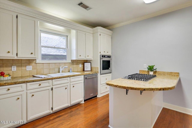 kitchen with stainless steel appliances, a sink, visible vents, white cabinetry, and light countertops