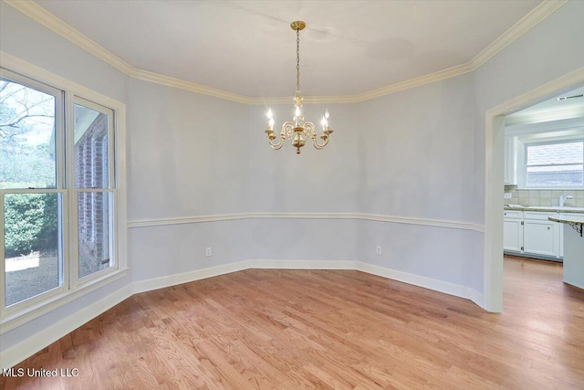 unfurnished room with light wood-type flooring, baseboards, a chandelier, and crown molding