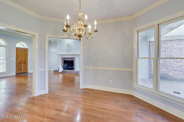 unfurnished dining area with baseboards, light wood finished floors, a brick fireplace, and crown molding