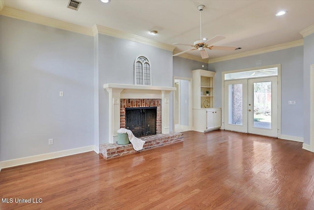 unfurnished living room with crown molding, a brick fireplace, wood finished floors, and baseboards