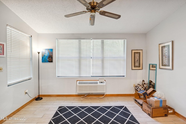 interior space featuring a wall unit AC, a textured ceiling, and ceiling fan