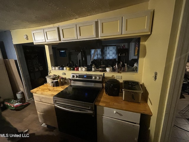 kitchen featuring stainless steel range with electric stovetop, butcher block counters, and a textured ceiling