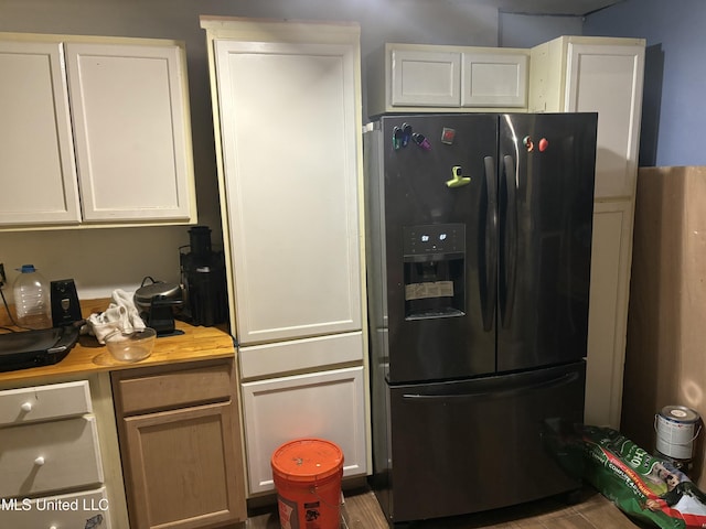 kitchen featuring white cabinetry, light countertops, and black fridge