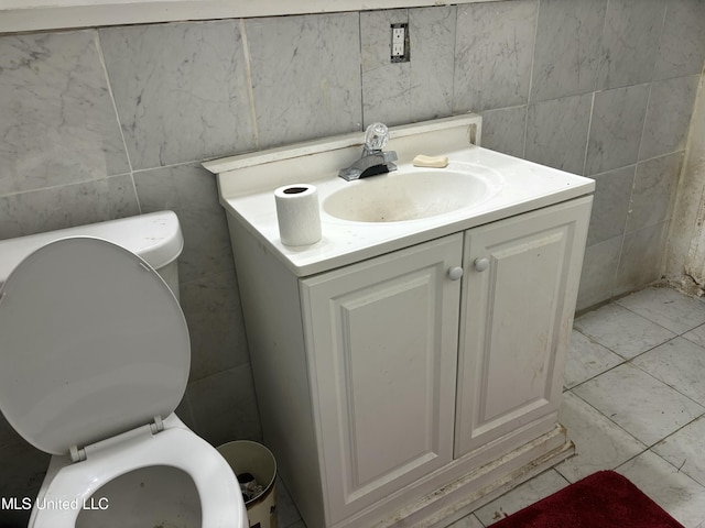 half bathroom with vanity, toilet, and tile walls