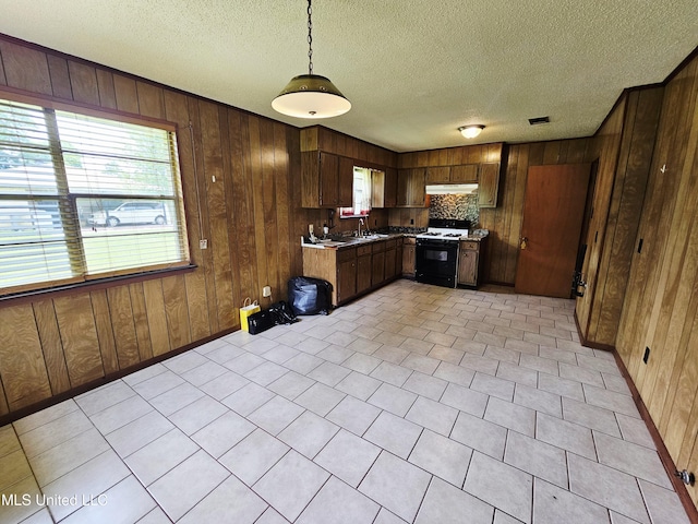 800 S Main St, Picayune, MS 39466 - kitchen featuring range with gas cooktop, under cabinet range hood, wooden walls, a textured ceiling, and pendant lighting