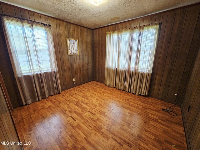 800 S Main St, Picayune, MS 39466 - spare room featuring healthy amount of natural light, light wood-style flooring, a textured ceiling, and wood walls