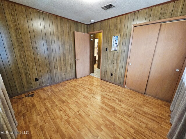 800 S Main St, Picayune, MS 39466 - unfurnished bedroom featuring wood finished floors, wooden walls, a textured ceiling, and a closet