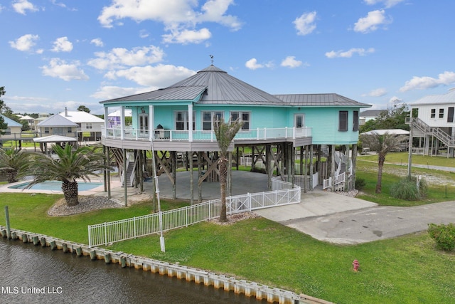 rear view of house with a carport, a water view, and a yard