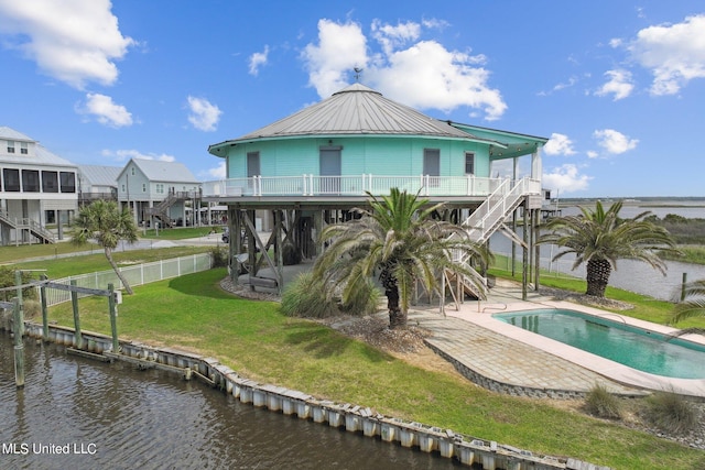 rear view of property with a patio, a water view, a fenced in pool, and a lawn