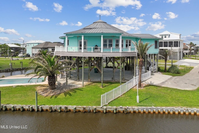 rear view of property with a lawn, a balcony, a water view, and a carport