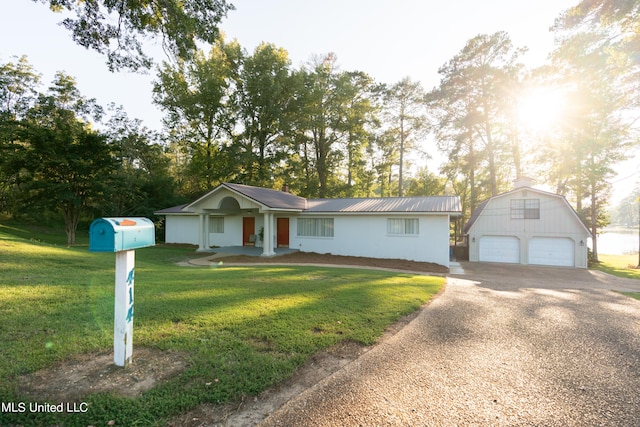 single story home featuring an outbuilding, a garage, and a front lawn