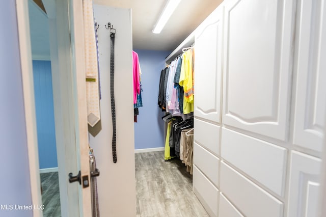 walk in closet with light hardwood / wood-style flooring