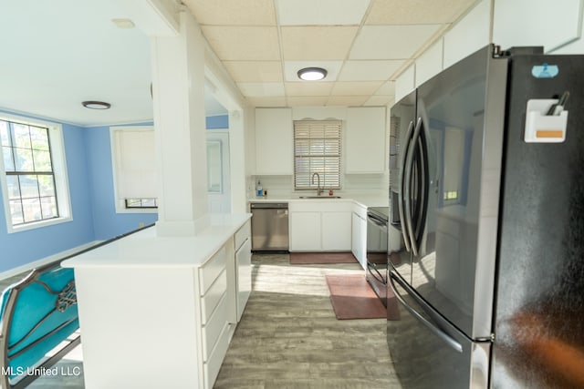 kitchen with backsplash, sink, appliances with stainless steel finishes, white cabinetry, and wood-type flooring