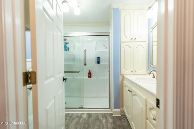 bathroom featuring ornamental molding, vanity, wood-type flooring, and walk in shower