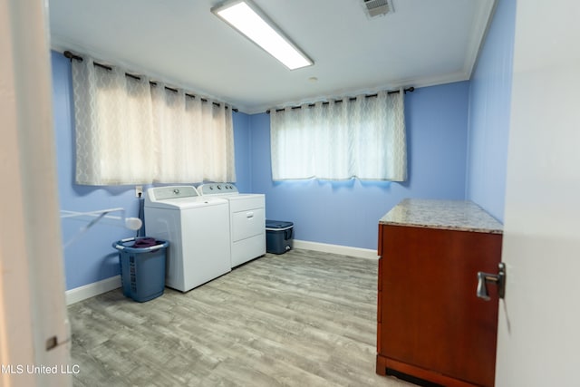 laundry area featuring light wood-type flooring, ornamental molding, and separate washer and dryer