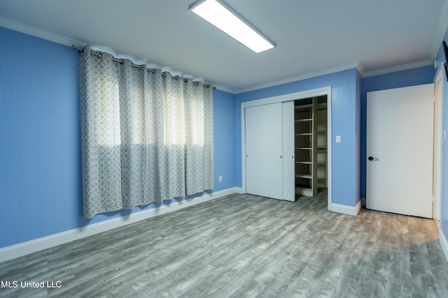 unfurnished bedroom with wood-type flooring, crown molding, and a closet