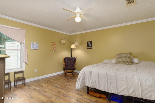 bedroom with ornamental molding, visible vents, a textured ceiling, and wood finished floors