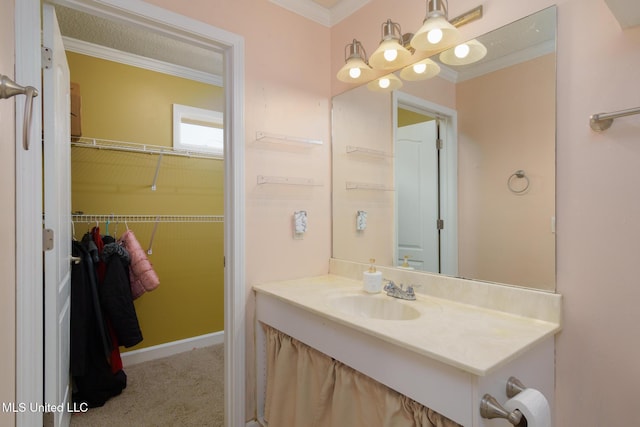 bathroom featuring a walk in closet, crown molding, and vanity