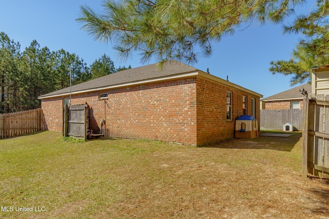 back of property with a yard, brick siding, and a fenced backyard