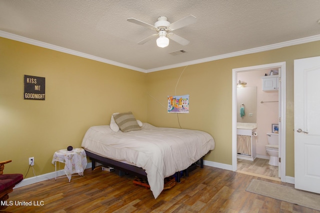 bedroom featuring a textured ceiling, ornamental molding, wood finished floors, and visible vents