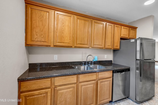 kitchen featuring dark stone countertops, brown cabinets, appliances with stainless steel finishes, and a sink