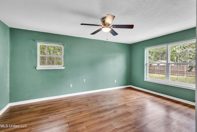 unfurnished room featuring a ceiling fan, baseboards, wood finished floors, and plenty of natural light