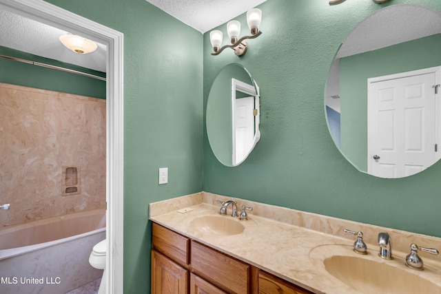 full bath with toilet, a textured ceiling, a sink, and double vanity