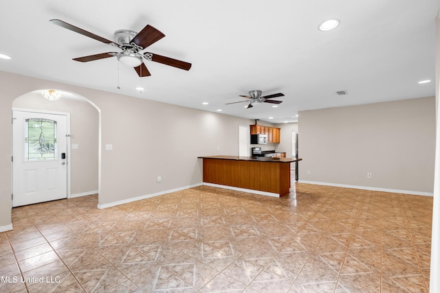 unfurnished living room featuring recessed lighting, arched walkways, a ceiling fan, and baseboards