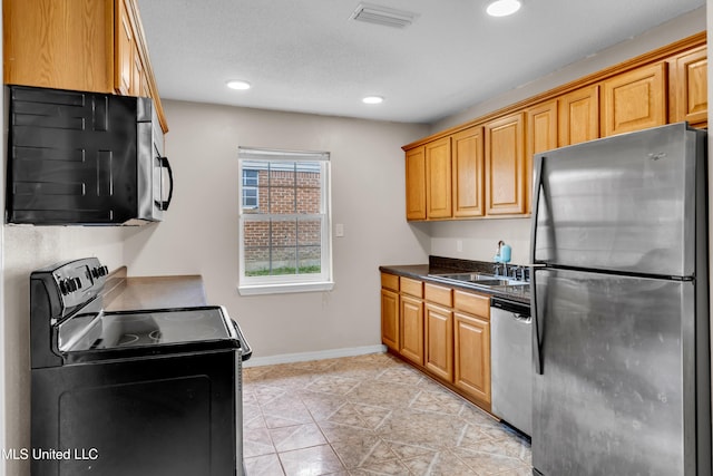 kitchen with recessed lighting, stainless steel appliances, dark countertops, a sink, and visible vents