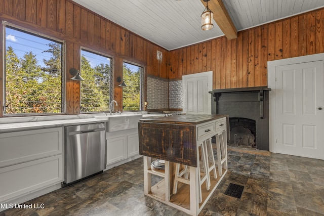 21021 Old River Rd, Vancleave, MS 39565 - kitchen featuring stainless steel dishwasher, stone finish floors, wooden walls, wood ceiling, and white cabinetry