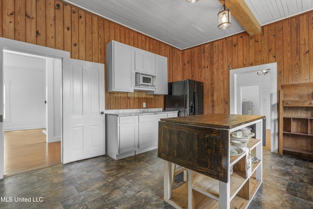 21021 Old River Rd, Vancleave, MS 39565 - kitchen with white microwave, black fridge, wood walls, wooden ceiling, and beamed ceiling