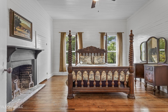 21021 Old River Rd, Vancleave, MS 39565 - bedroom with hardwood / wood-style flooring, a fireplace with raised hearth, wooden walls, and ceiling fan