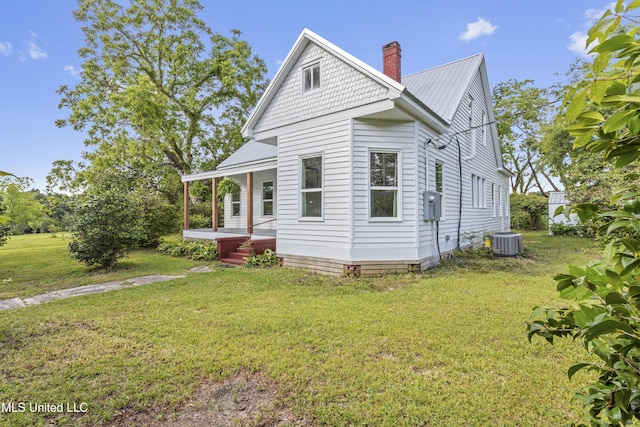 21021 Old River Rd, Vancleave, MS 39565 - view of property exterior featuring a yard, a chimney, metal roof, covered porch, and cooling unit