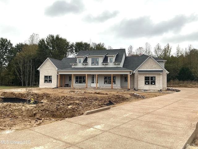 view of front of home featuring covered porch and a shingled roof