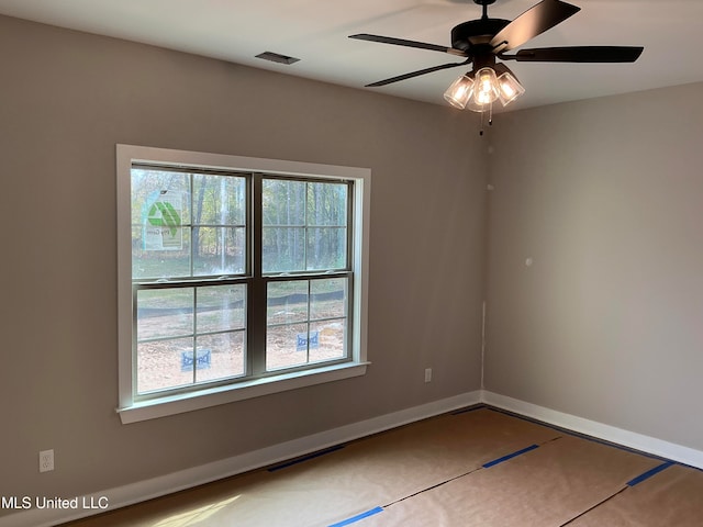 spare room with a healthy amount of sunlight, a ceiling fan, visible vents, and baseboards