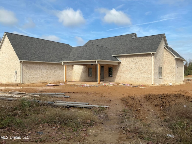 rear view of house with stucco siding, roof with shingles, and a patio