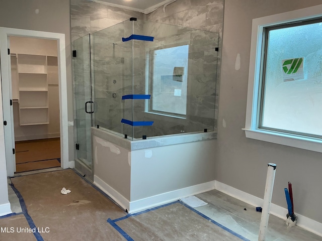 bathroom with a stall shower, baseboards, and a walk in closet