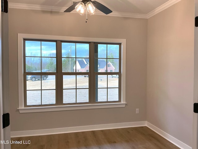 empty room featuring dark wood-type flooring, crown molding, and baseboards