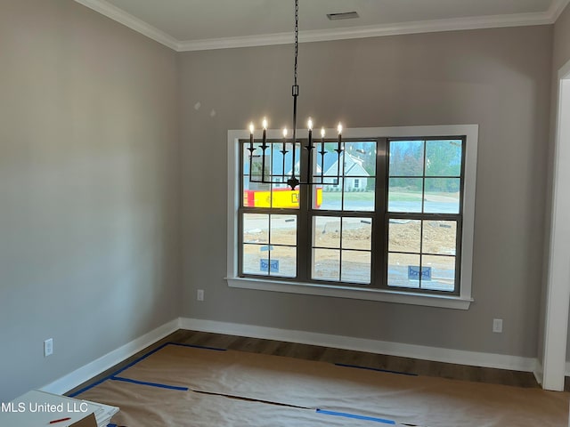 unfurnished dining area featuring wood finished floors, visible vents, baseboards, ornamental molding, and an inviting chandelier