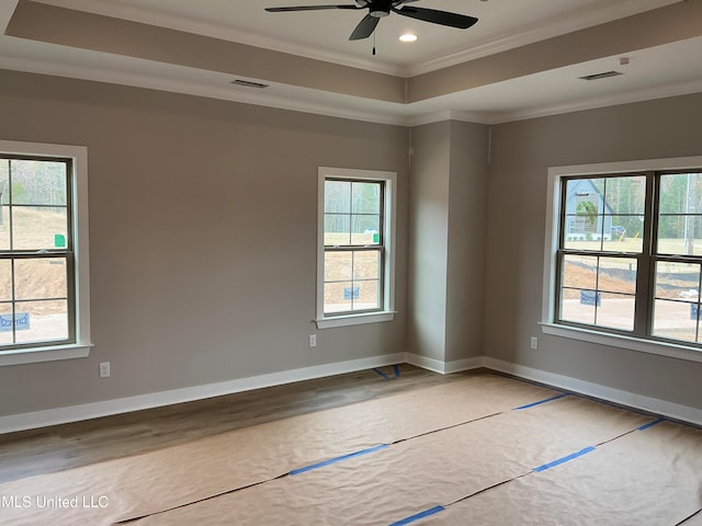 spare room with ornamental molding, a raised ceiling, visible vents, and baseboards