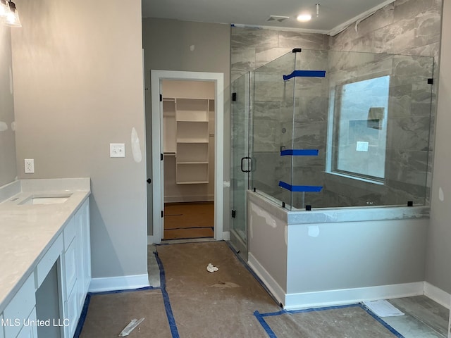 full bathroom featuring baseboards, a shower stall, vanity, and a spacious closet