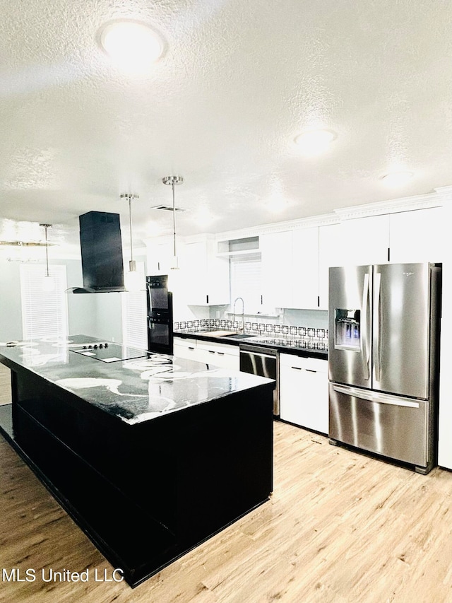 kitchen featuring white cabinets, decorative light fixtures, stainless steel appliances, and extractor fan