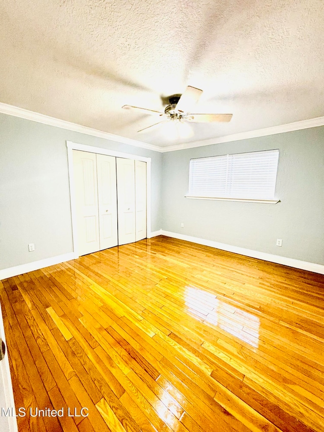 unfurnished bedroom with a textured ceiling, wood-type flooring, a closet, and ceiling fan