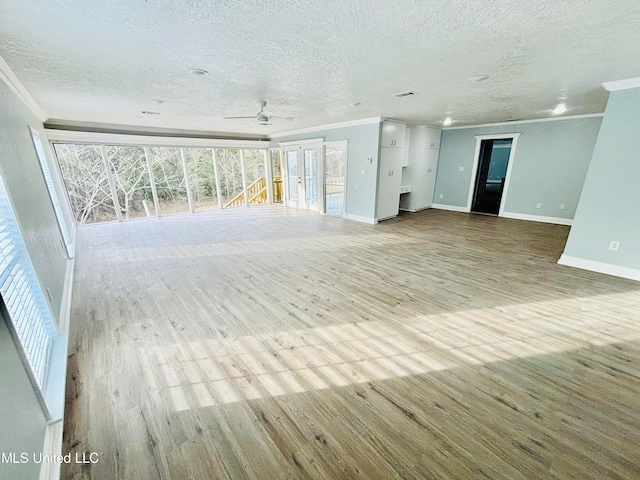 unfurnished living room with light hardwood / wood-style flooring, ornamental molding, a textured ceiling, and ceiling fan