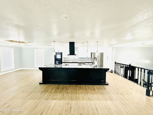 kitchen featuring light wood-type flooring, an island with sink, stainless steel fridge, white cabinets, and ventilation hood